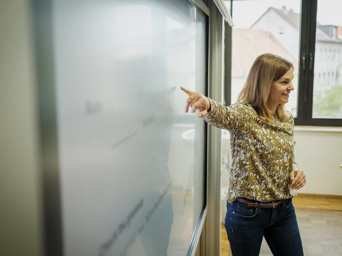 Lehrsituation: Lehrkraft zeigt auf ein Smartboard