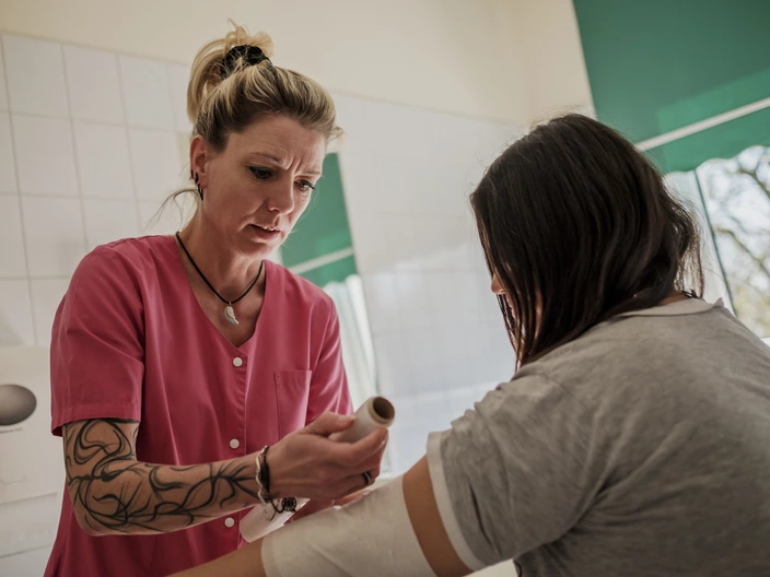 Pflegekraft versorgt eine Patientin mit einem Verband